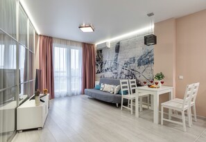 A modern living room with a sofa, dining table, chairs, and a large window with curtains. - Comfortable apartment for 4 guests (Minsk)