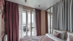 Ett hotellrum med en stor säng, utsikt över omgivningarna och en skjutdörr i glas.