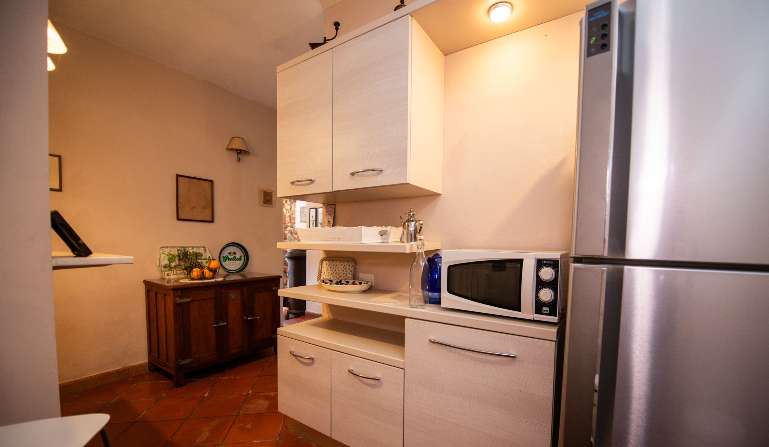 Una cocina compacta con un refrigerador de acero inoxidable, un microondas y armarios de madera.