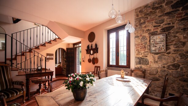 A dining area with a wooden table, chairs, a potted plant, and a staircase. - Villa Catharina in Ro Volciano (Roe Volciano)