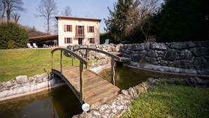 A house with a stone wall and a wooden bridge over a pond. - Villa Catharina in Ro Volciano (Roe Volciano)