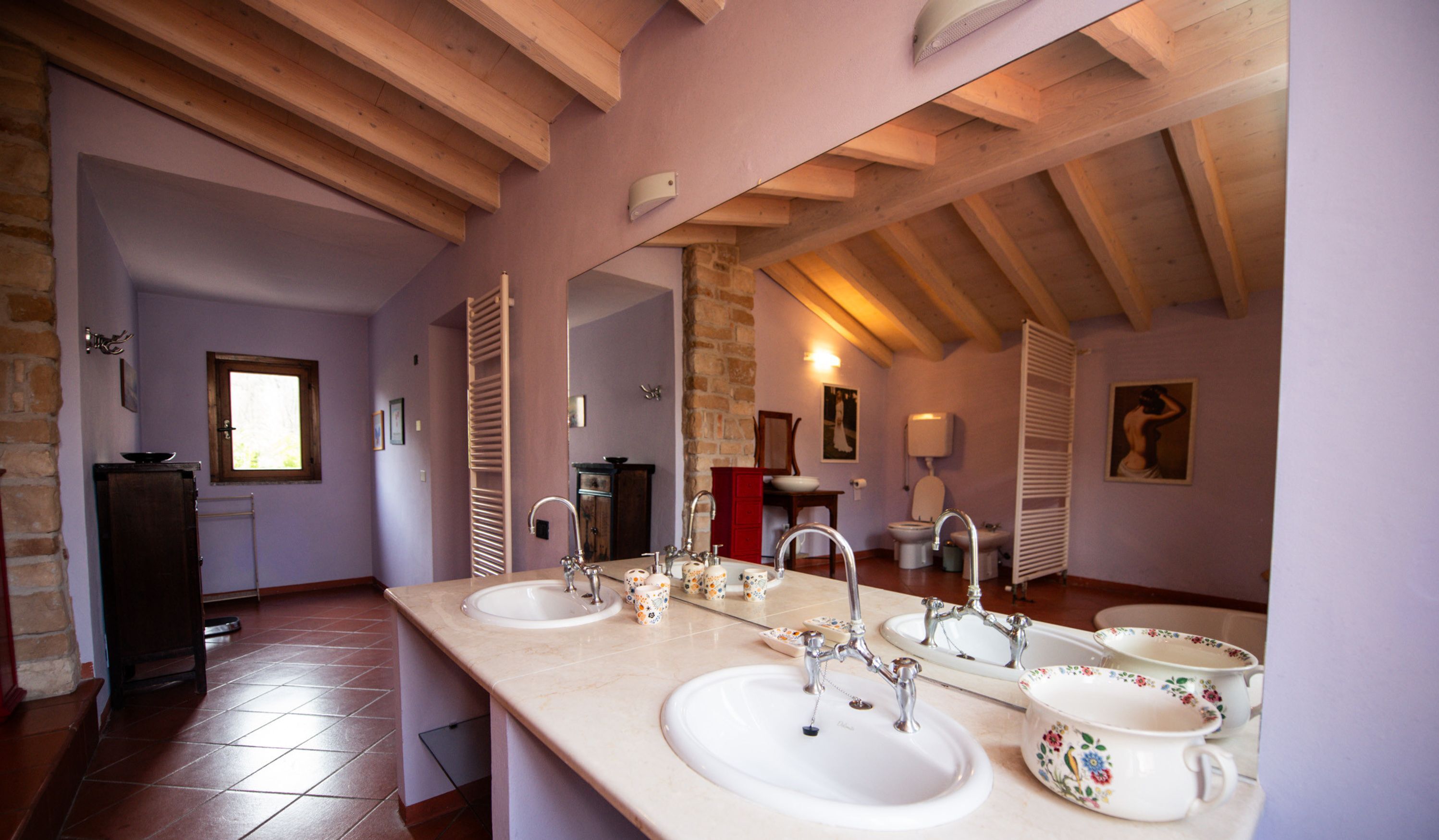 A bathroom with two sinks, a mirror, and a toilet.