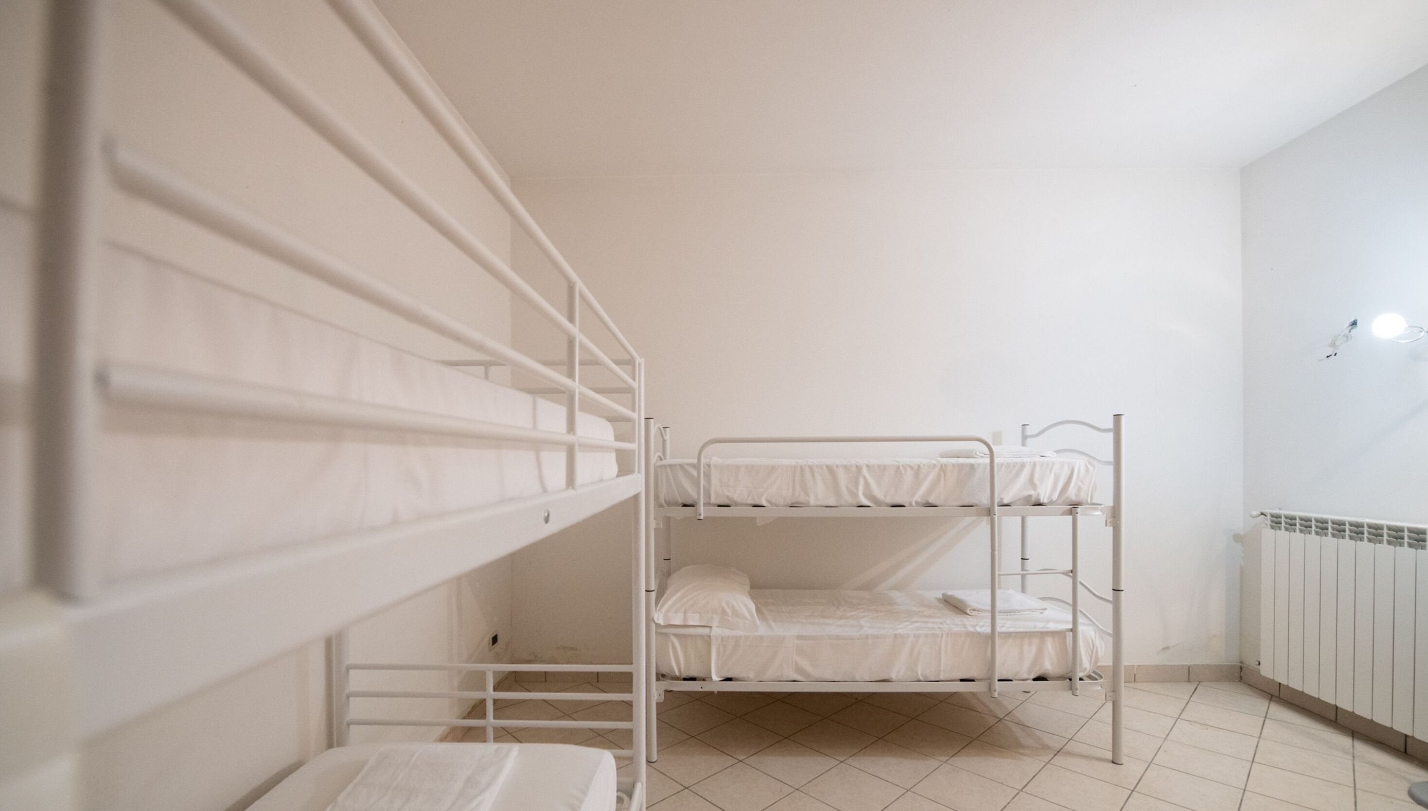 A bunk bed room with white metal railings and a tiled floor.