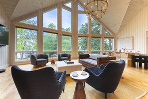 A spacious room with large windows, a cozy seating area, and a dining setup.