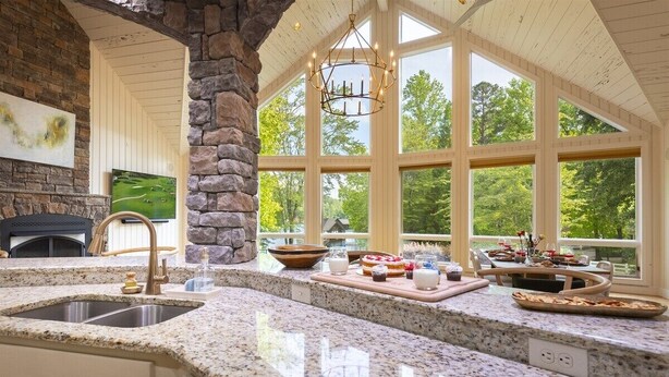 A spacious kitchen with granite countertops, a stone column, and large windows offering a view of the outdoors.