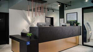 Een receptiebalie met een modern ontwerp, een plantje op de toonbank, en een bordje voor rolstoeltoegankelijkheid.