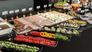Un bufé con diversas opciones de comida, incluyendo carnes, quesos, ensaladas y verduras.