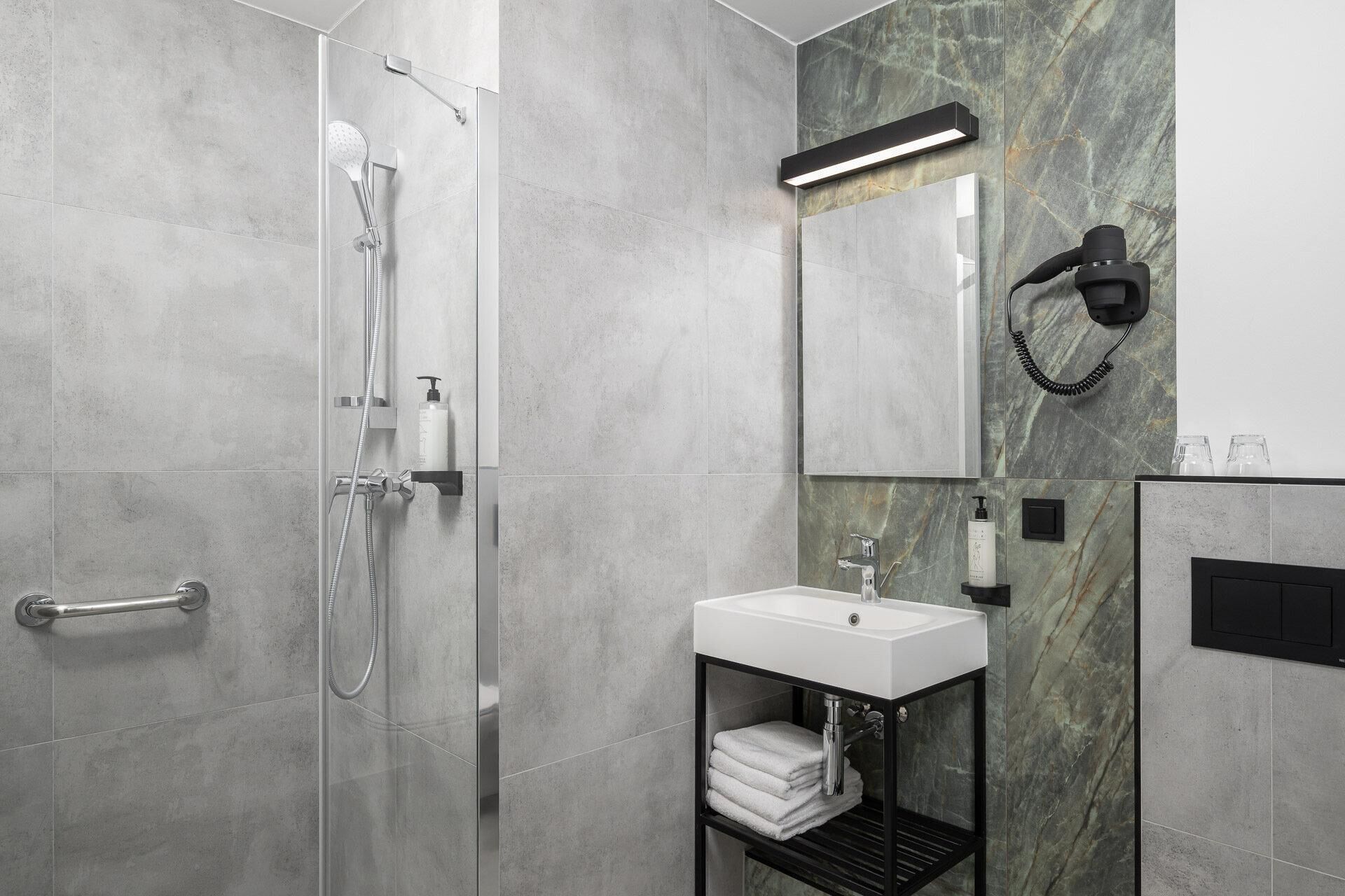 A modern bathroom with a glass-enclosed shower, a vanity with a sink, and a marble backsplash.