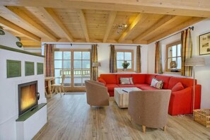 A cozy living room with a fireplace, a red sofa, and a wooden ceiling. - Scenic Valley Chalet in Austria (Wald im Pinzgau)