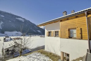 A wooden building with a white facade, a balcony, and a view of a snowy landscape with mountains in the background. - Scenic Valley Chalet in Austria (Wald im Pinzgau)