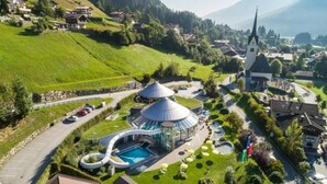 A resort with a pool, a water slide, and a church in the background. - Scenic Valley Chalet in Austria (Wald im Pinzgau)