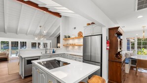 Une cuisine moderne dotée d’un grand îlot central, de meubles blancs et d’appareils électroménagers en acier inoxydable.