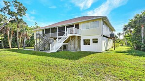 A two-story house with a porch, a staircase, and a fenced yard.