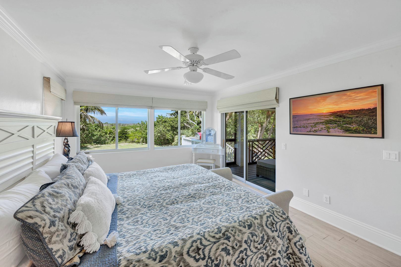 Une chambre à coucher avec un lit, un ventilateur de plafond, une fenêtre donnant sur un beau paysage et un tableau accroché au mur.