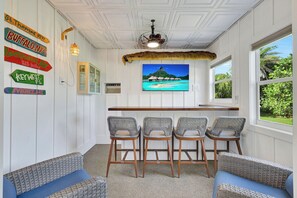 A bar area with wicker chairs, a wooden counter, and a large window with a view of a beach. - Rabbit road oasis just a short stroll to The Gulf! (Sanibel)