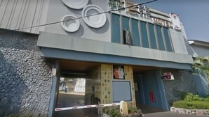 Ein Gebäude mit modernem Design, das ein großes Logo an der Fassade und einen verschlossenen Eingang zeigt.