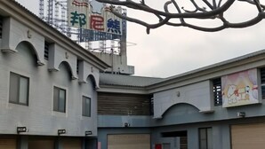 Ein Gebäude mit mehreren Garagentoren, einer großen Schrifttafel mit chinesischen Schriftzeichen und einem Wandgemälde von einem Bären.