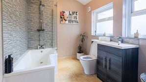 A modern bathroom with a bathtub, toilet, and vanity. - Cornwall House Home from Home Stay (Hartlepool)