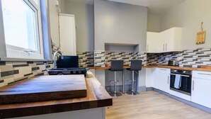 A modern kitchen with a wooden countertop, a built-in stove, and a tiled backsplash. - Cornwall House Home from Home Stay (Hartlepool)