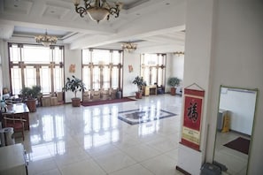 Un hall d’entrée spacieux, doté de grandes fenêtres, de plantes en pot et d’un lustre.