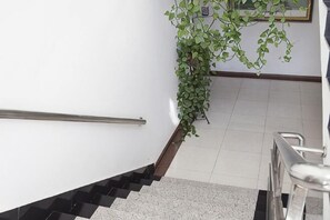 A staircase with a handrail, a potted plant, and a tiled floor. - Yongquan Hotel (Mohe)