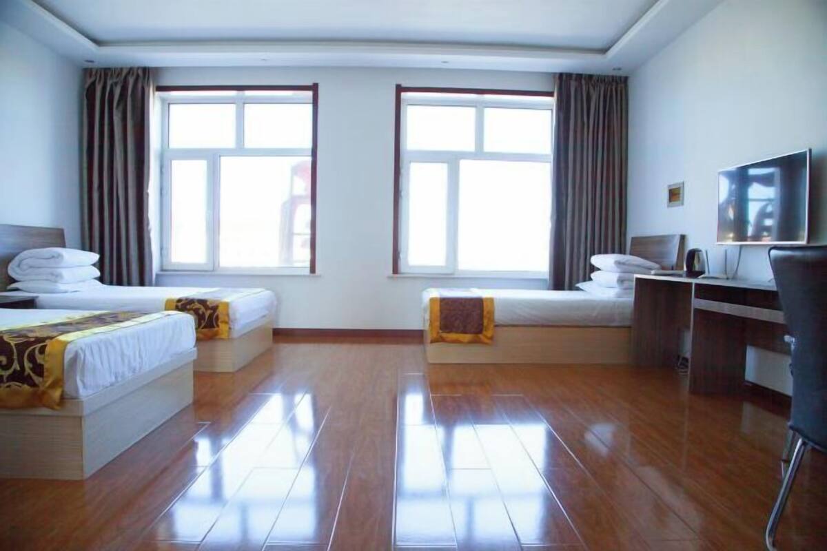 Une chambre d’hôtel avec deux lits, un bureau, une chaise et un téléviseur.
