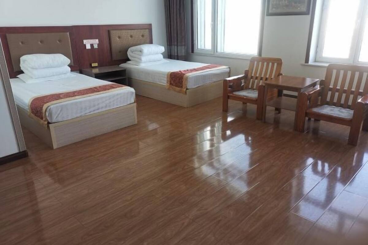 Une chambre d’hôtel avec deux lits, un plancher en bois, une petite table et une chaise.
