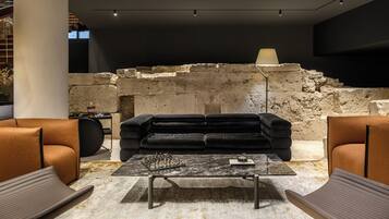 A modern interior with a stone wall, a black sofa, and a chess table.