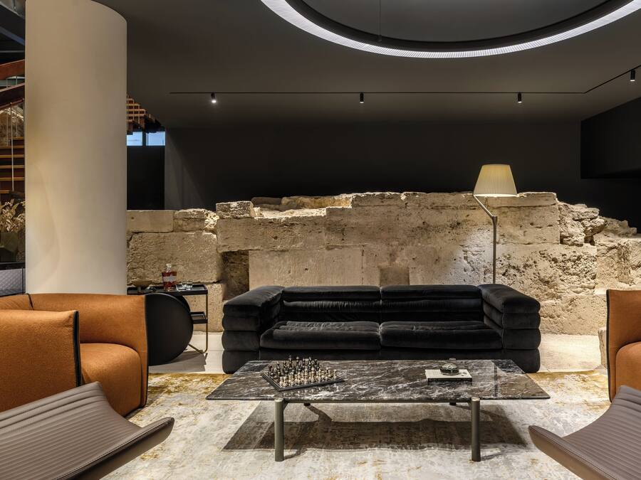 A modern interior with a stone wall, a black sofa, and a chess table.