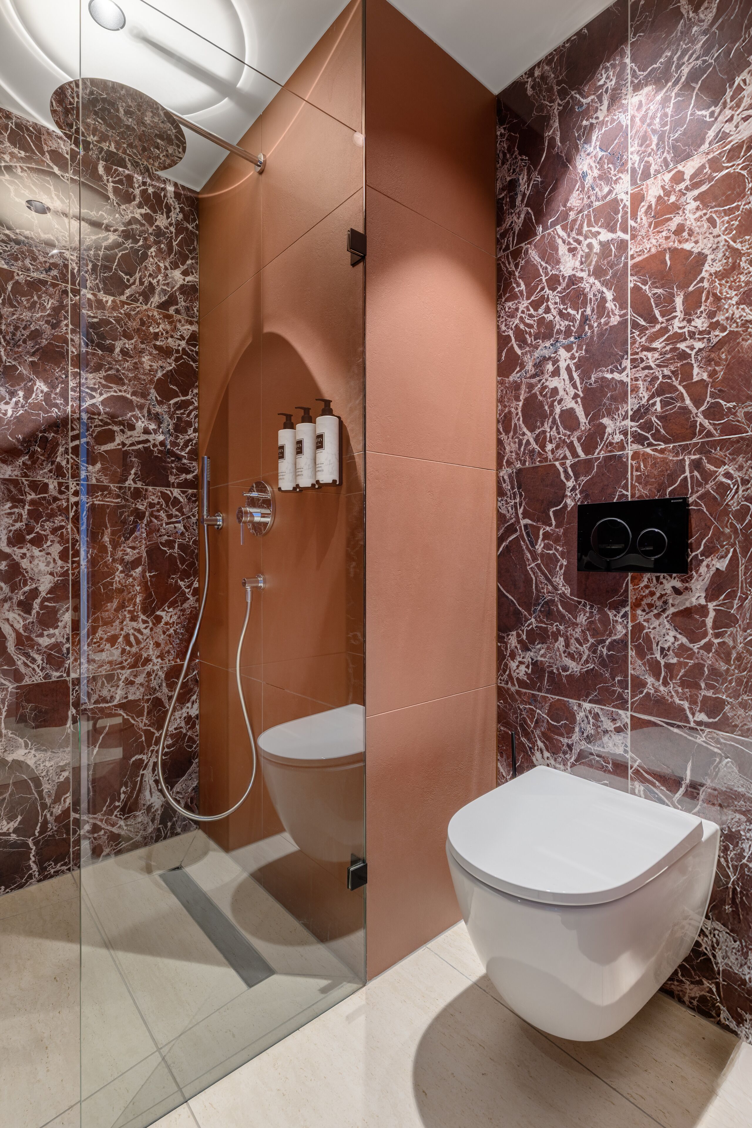 A modern bathroom with a glass-enclosed shower, a white toilet, and marble-patterned walls.