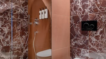 A modern bathroom with a glass-enclosed shower, a white toilet, and marble-patterned walls.