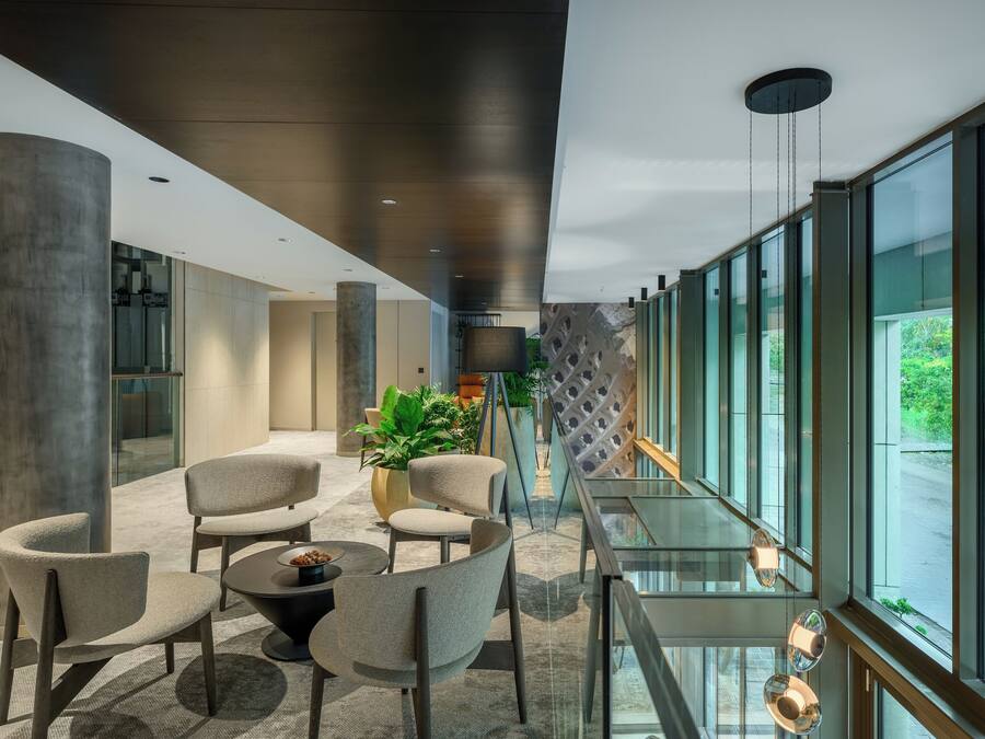 Eine moderne Lobby mit Sitzgelegenheiten, großen Fenstern und Blick auf Grünflächen.