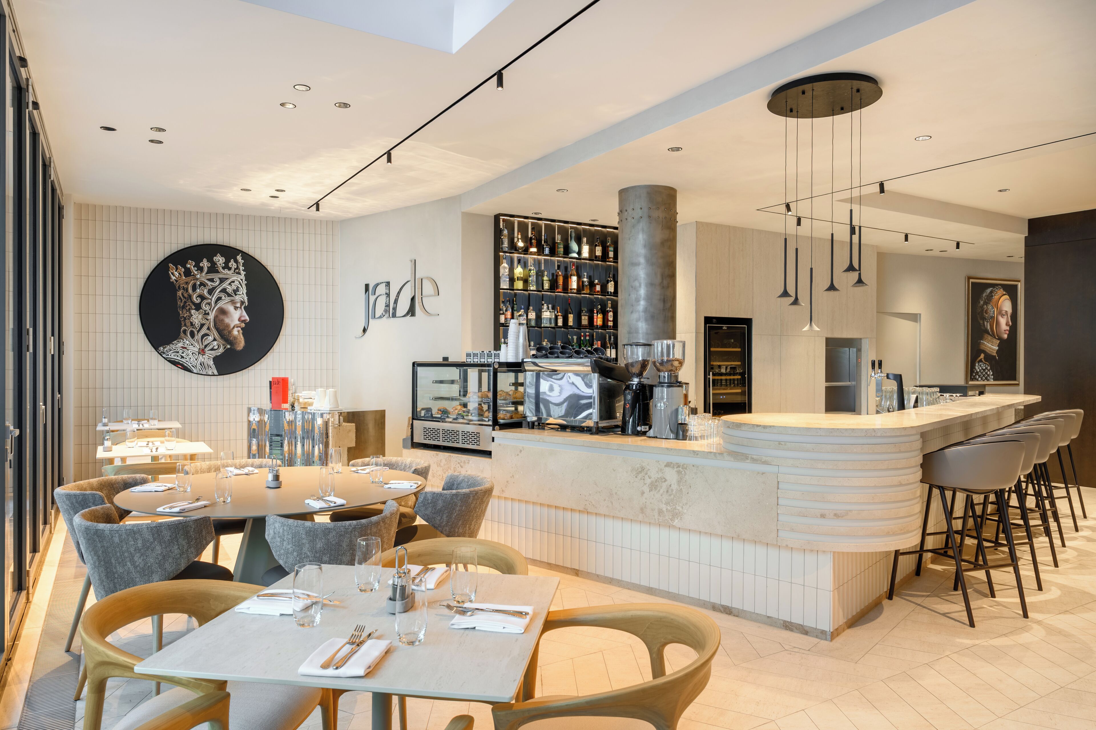 A modern restaurant with a bar area, round tables, and bar stools.