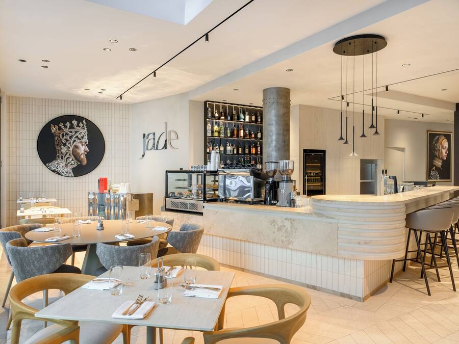 A modern restaurant with a bar area, round tables, and bar stools.