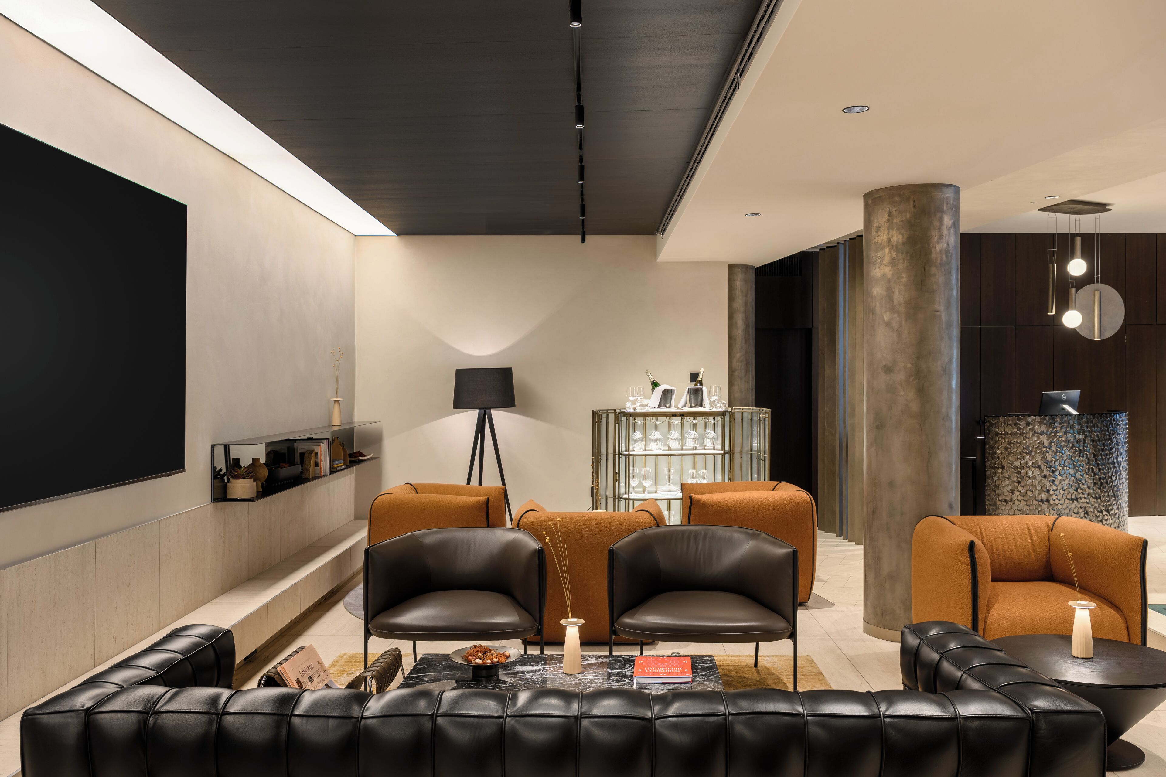 Ein modernes Wohnzimmer mit Ledersofas, einem Couchtisch, einem Bücherregal und einer dekorativen Lampe.