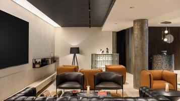 Ein modernes Wohnzimmer mit Ledersofas, einem Couchtisch, einem Bücherregal und einer dekorativen Lampe.