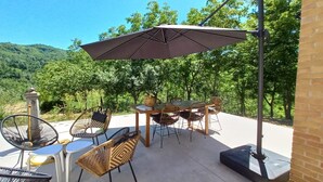 An outdoor patio with wicker furniture, a table, and an umbrella.