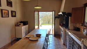 A compact kitchen with a dining area, a view through the open door, and a small dining table set with plates.