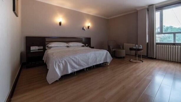 A hotel room with a bed, a chair, a small table, and a window. - Yudu Hotel (Hotan City)
