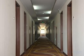 A hotel corridor with doors on both sides, carpeted floor, and overhead lighting. - Yudu Hotel (Hotan City)