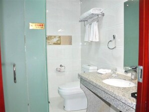 A bathroom with a toilet, sink, and a mirror.