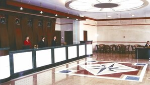 A hotel reception area with a reception desk, several chairs, and a large geometric floor design. - Yudu Hotel (Hotan City)