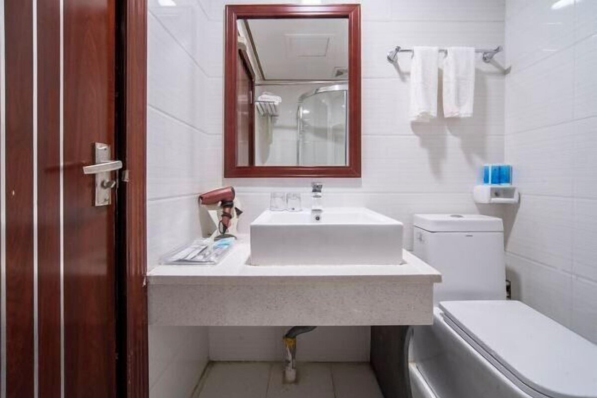 A bathroom with a white sink, a mirror, a toilet, and a shower.