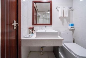 A bathroom with a white sink, a mirror, a toilet, and a shower. - Yudu Hotel (Hotan City)
