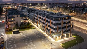 A multi-story hotel with a modern design, featuring a rooftop terrace and a parking lot. - Pileckiego Residence (Warsaw)