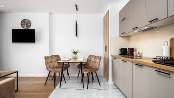 A modern kitchen with a wooden countertop, a built-in oven, and a coffee machine.