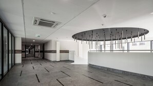 A modern hotel lobby with a long corridor, a reception desk, and a large window. - Pileckiego Residence (Warsaw)