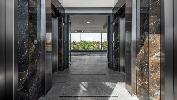 A modern elevator lobby with marble walls and a clear view of the outdoors. - Pileckiego Residence (Warsaw)