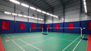 An indoor badminton court with a high ceiling and red curtains. - SPR Paradise Resort (Vanur)