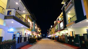 A nighttime view of a residential building with multiple floors, balconies, and a paved walkway. - SPR Paradise Resort (Vanur)